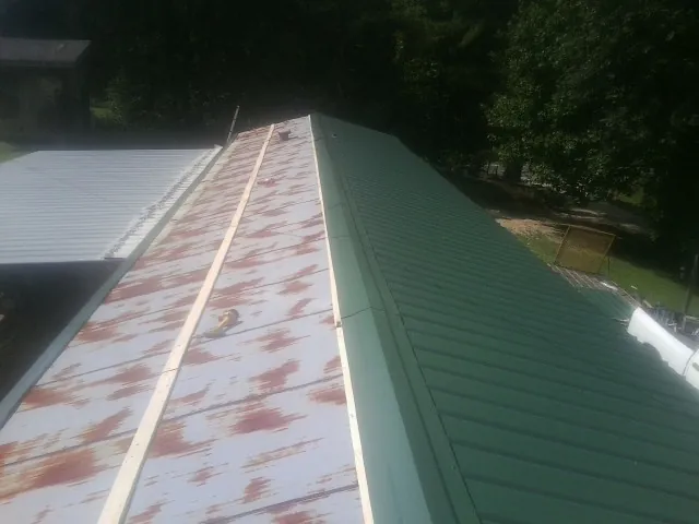 Old rusted panels beside newly installed green metal roofing — Wind Damage Roof Repair by Roofing Brothers in East Islip