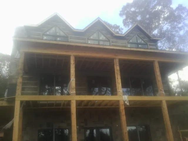 Dormers and porch framing on a large log home under construction — Roof Coating work by our crew in East Islip
