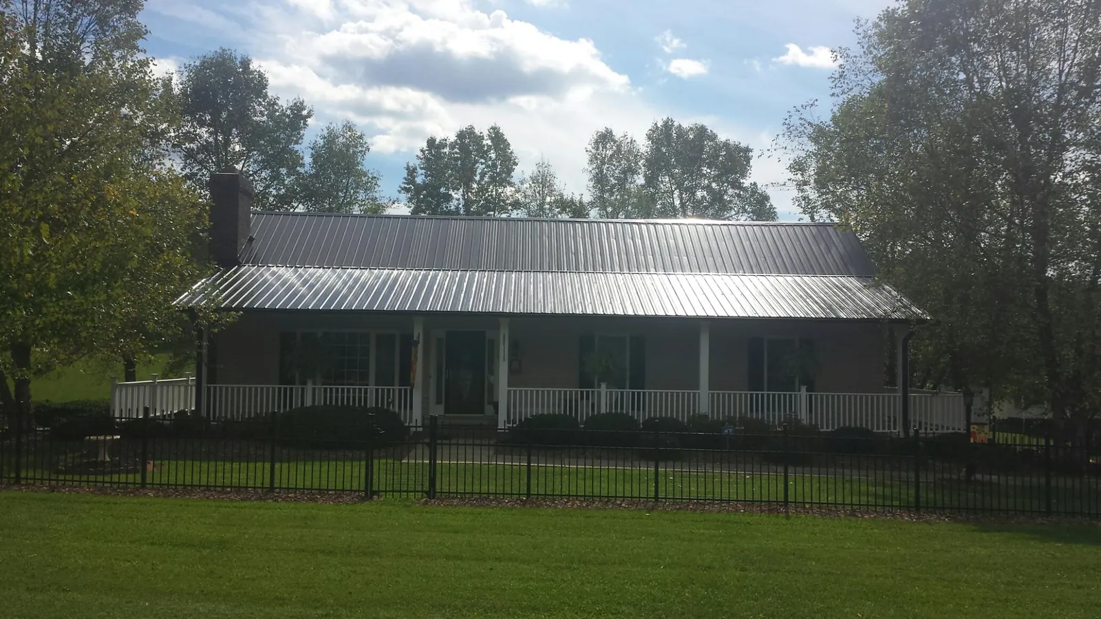 Gray metal roof on a brick ranch with a full width front porch — Gutter Guard Installation work by our crew in East Islip