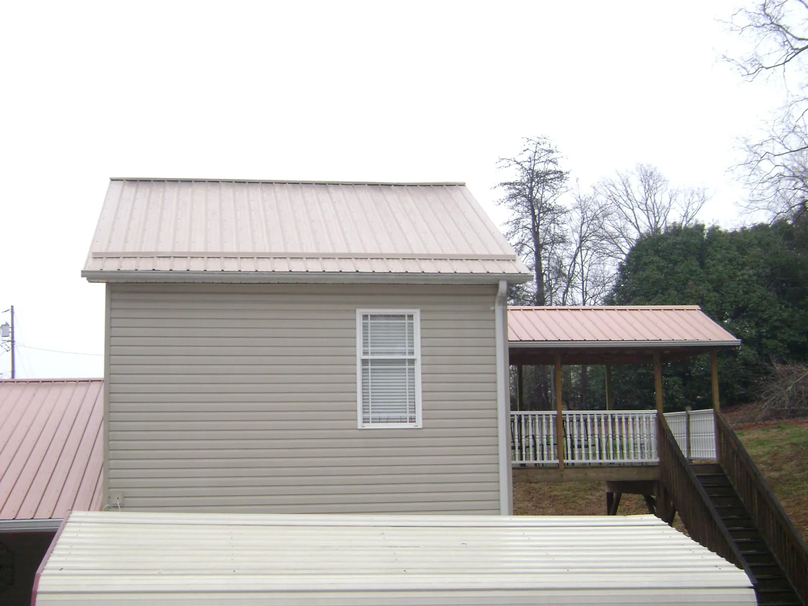 Tan metal roofs on a two story addition and attached porch, from a Roof Replacement job in East Islip