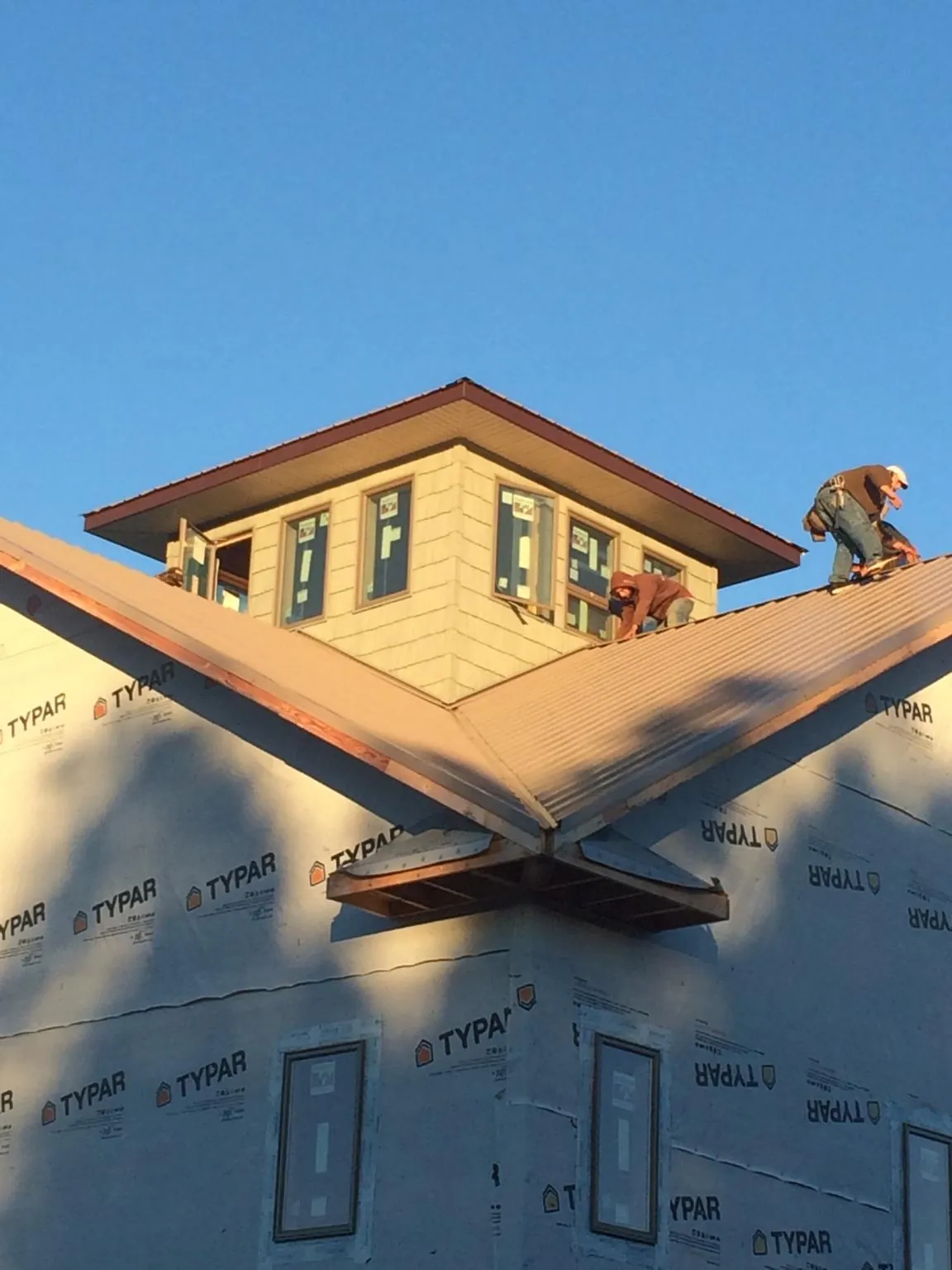 Roofers working around a rooftop cupola on a new metal roof at sunset — Roof Waterproofing in East Islip by Roofing Brothers